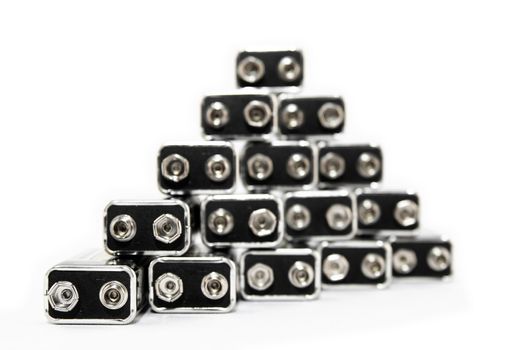 Nine volt batteries forming a pyramid, on white background. Focus on the closest left battery, shallow depth of field.