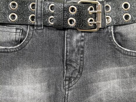 Closeup of black denim jeans with black leather belt and metal buckle.