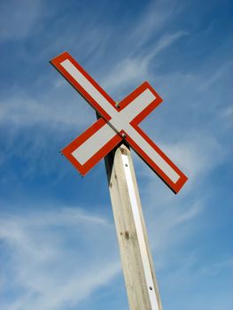 Red railroad crossing sign against the blue sky.