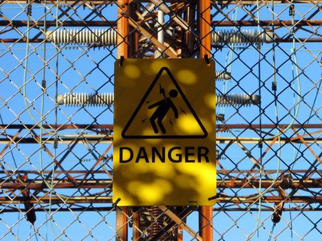 High voltage danger sign at the chain link fence of a power station.