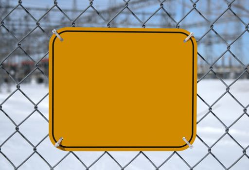 Blank high voltage danger sign with copy space at the chain link fence of a power station.
