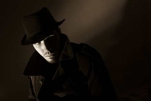 Sepia toned noir portrait of suspicious looking young man. Harsh highlights and shadows.