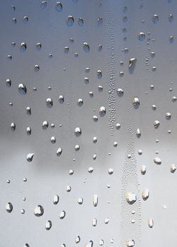 Water drops of metallic color on glass.