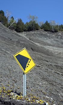 Yellow falling rocks sign on the mountain slope.