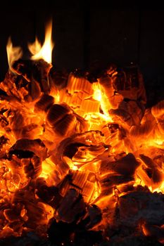 Glowing coals and fire flames in the fireplace.