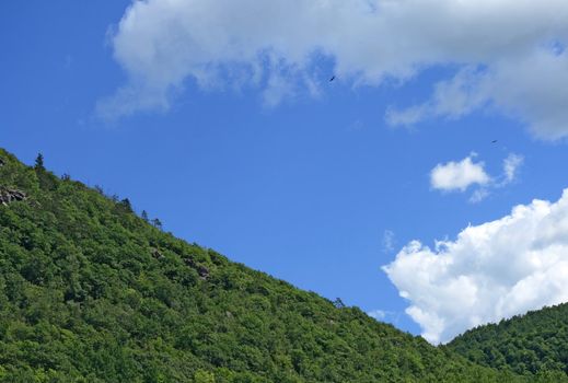 Green mountain slope and the blue sky with clouds.