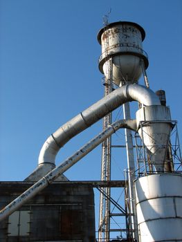 Shot of an old factory and water tower on a blue sky background.