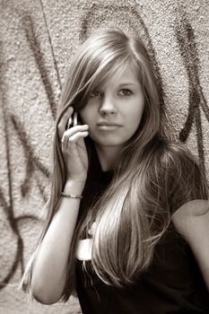 The girl - teenager with the phone on a background of a wall
