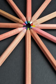 Colored pencils in star shape against black background