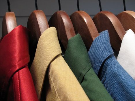 Shirts of different colors on wooden hangers.