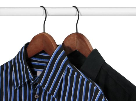 Closup of shirts on wooden hangers in a closet, on white background.