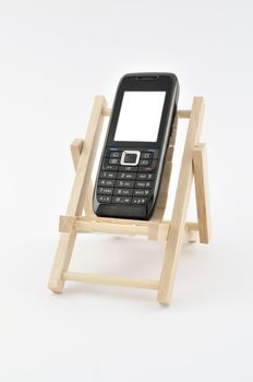 Modern cell phone siting in a miniature deck chair