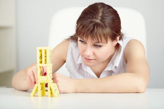 Girl is focused to build a tower with a domino on the table