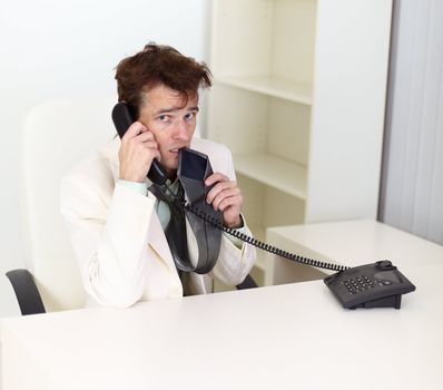 Young disheveled businessman talking on the phone very excited