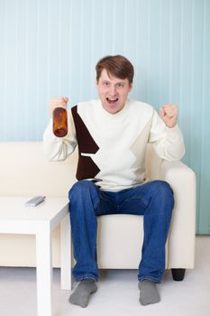 Football fan sitting on the sofa with a TV and beer