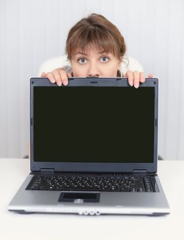 Young beautiful girl hiding behind a laptop screen