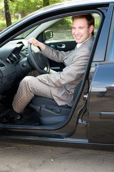 smiling businessman in the car at the wheel