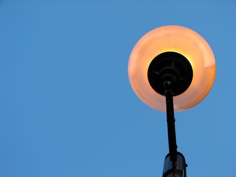 Street light against the clear blue sky, view from below.