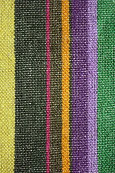 Texture of a rustic linen fabric with colorful stripes.