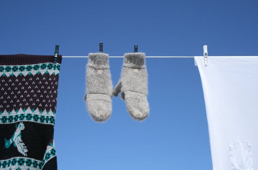 Spring laundry - mittens, sweater and t-shirt hanging to dry on a clothes-line.