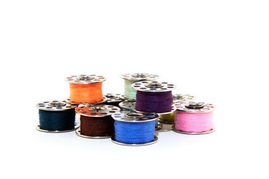 Colorful spools of thread for sewing machine, on white background.
