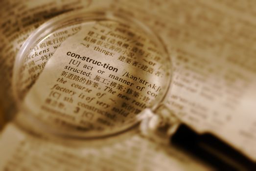 Focus on construction word by magnifier in book.