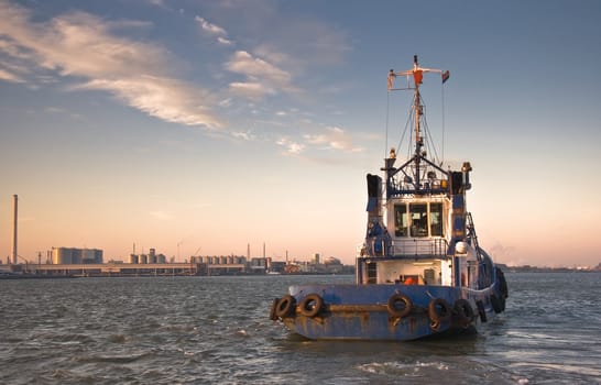 Tugship leaving port at sunrise and sailing down the river