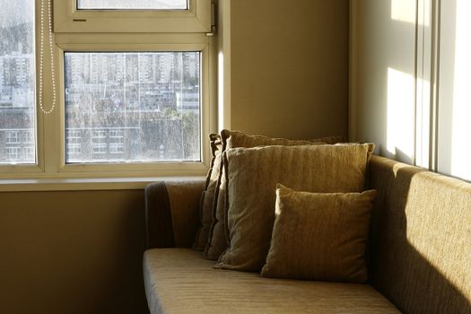 Morning sunrays at cozy brown sofa with pillows