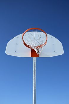 Basketball backboard, hoop and net against the blue sky.