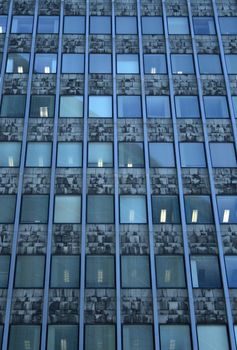 Working day in the office building. Windows with lights.