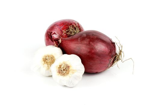 Two raw unpeeled red onions and two bulbs of garlic on a reflective white backgrounds