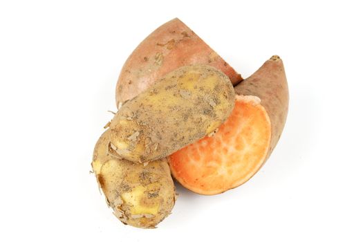 Sweet Potato cut in half with a small brown potato on a reflective white background