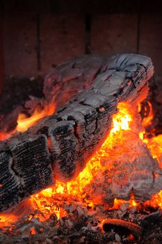 Fireplace - burning wood log turning into ash, and ember.