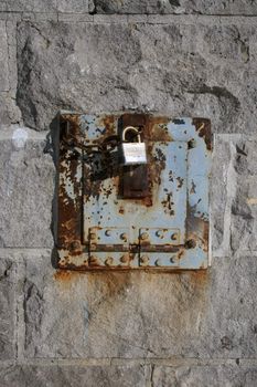 Iron lock and rusty metal on a stone wall.