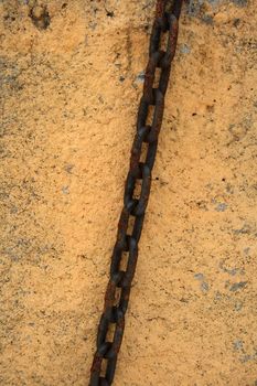 Rusty chain on a painted stone wall.