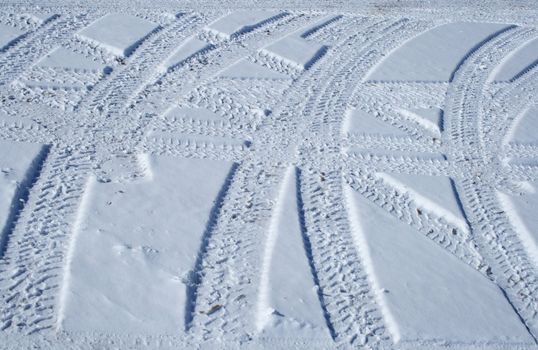 Vehicle tracks crossing the snowy winter terrain in different directions.
