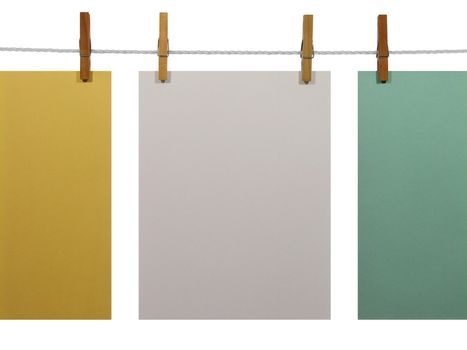 White, green and yellow blank paper sheets on a clothes line, isolated on white background. With clipping path.