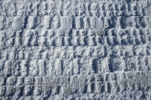 Car tracks imprinted in snow.