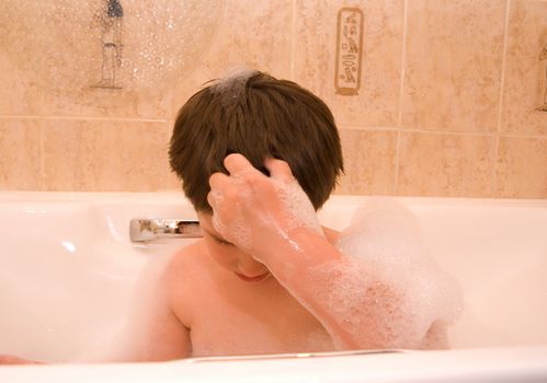 little boy is sitting in bathtun with foam