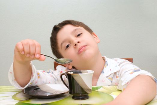 littly boy is playing with spoon at the table