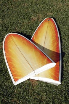 A Broken Yellow, Orange Surfboard On A Green Grass Field, Result Of Dangerous Surfing Conditions