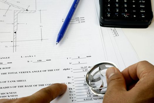 Engineer check his Design Calculation with calculator and machine parts