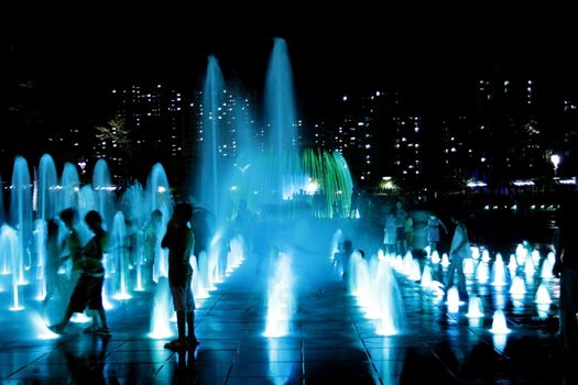 Series of fountain with children palying and building in the background