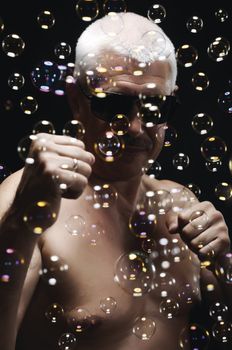 Senor man in sunglasses and soap bubbles on black background 