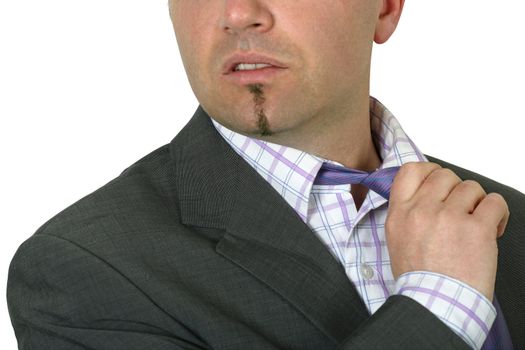 Exasperated businessman in his thirties loosening his tie.  Focus is on the tie, face is slightly blurred.
