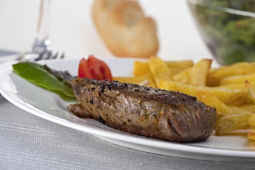 closeup of a beef steak with french fries on a white background