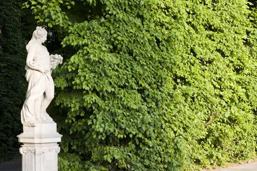 monument of a woman on a green leafes wall background