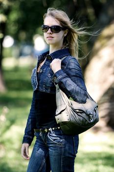 Walking young woman in black sunglasses and jeans