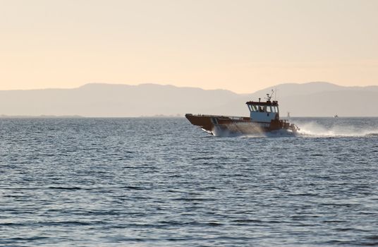 An Oslo fjord coatsguard boat, speeding in a spray of water 
