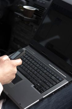 businessman inside car with laptop and phone
